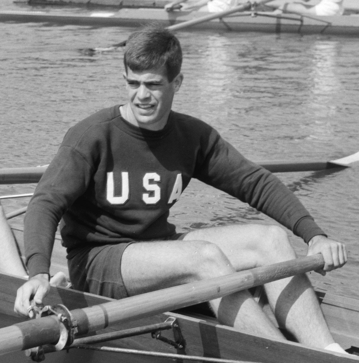 Boyce Budd '57 in his Team USA sweatshirt holding oars in a shell boat