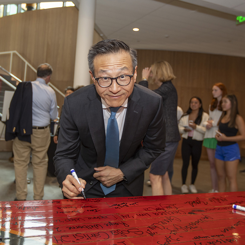 Joe Tsai '82 signing the cut-out section of the old basketball jump circle at the dedication of Tsai Field House.