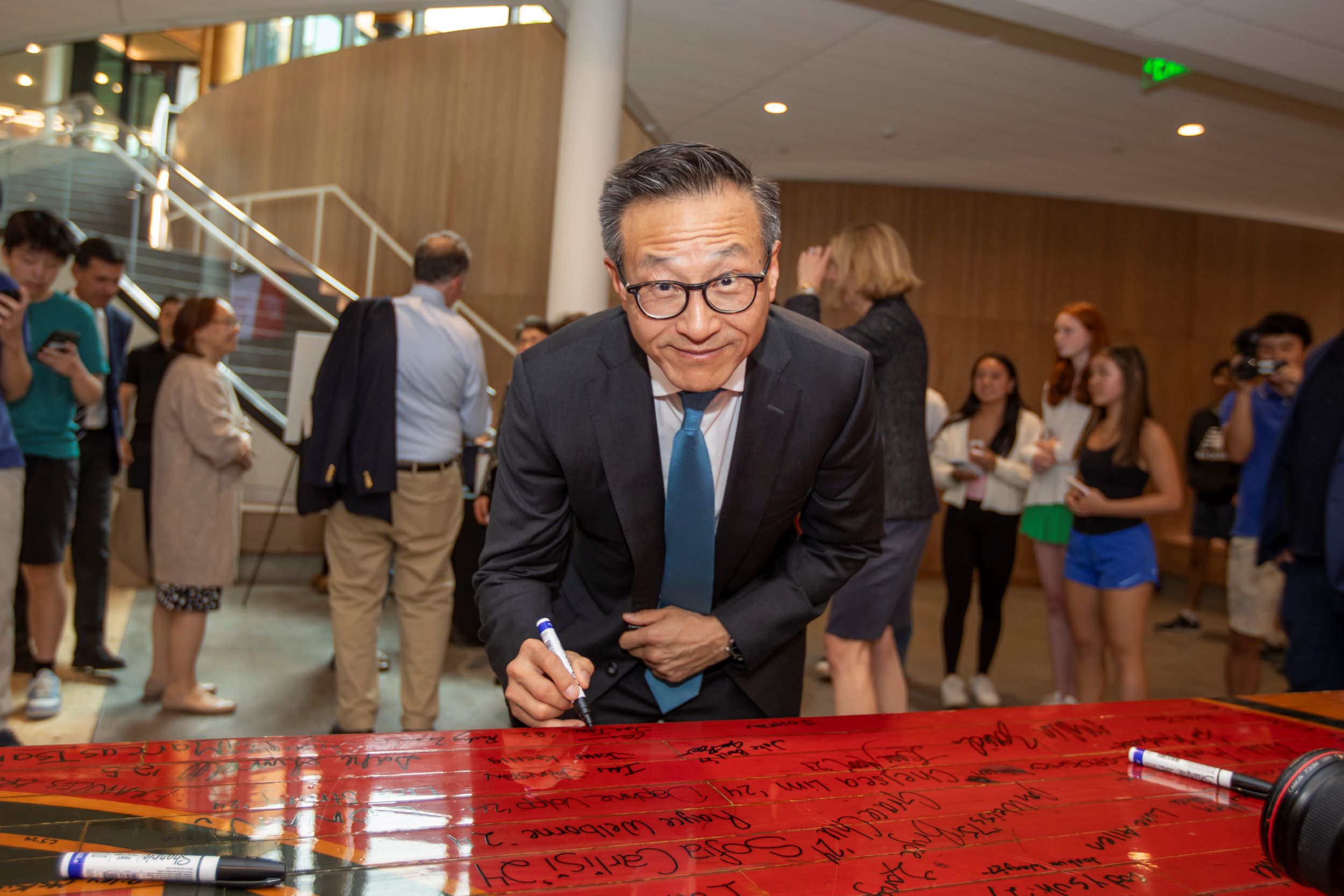 Joe Tsai '82 signing the cut-out section of the old basketball jump circle at the dedication of Tsai Field House.