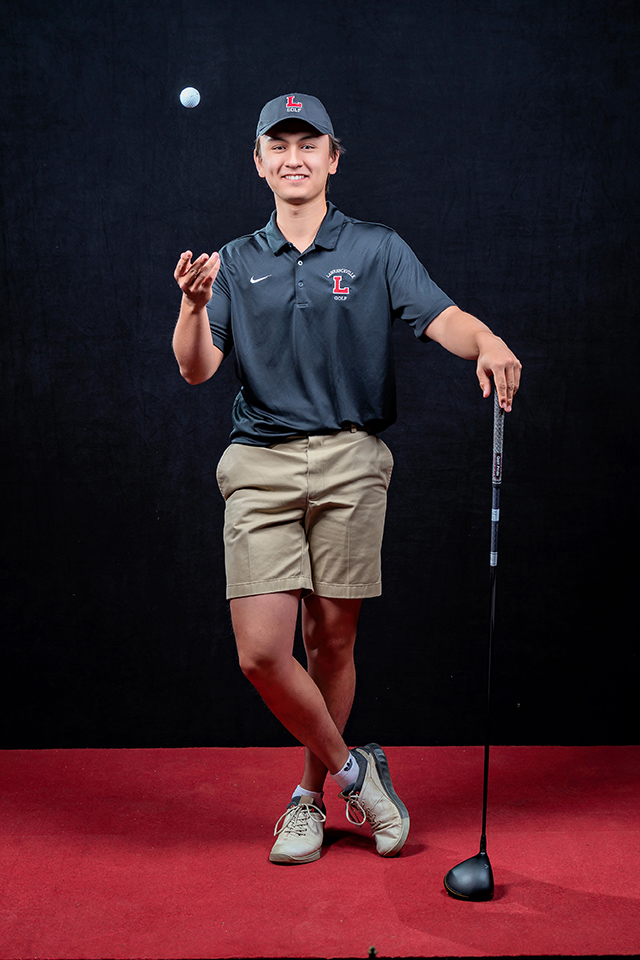 Leaning on his golf club, Adrian Jordan '24 tosses a golf ball to himself with a his right hand while wearing a Lawrenceville golf uniform.