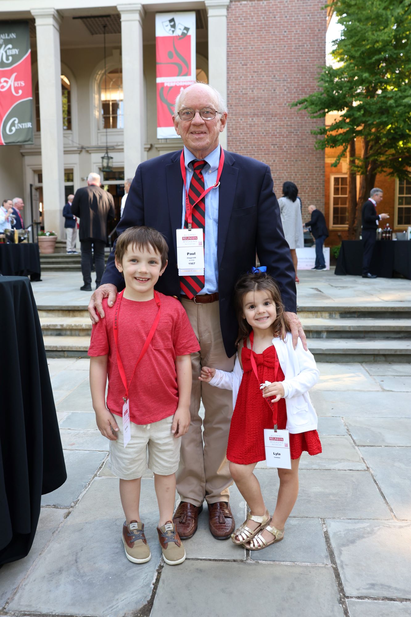 Paul Fitzgerald '67 P'03 stands with his two grandchildren in front of the Kirby Arts Center at Alumni Weekend 2024.