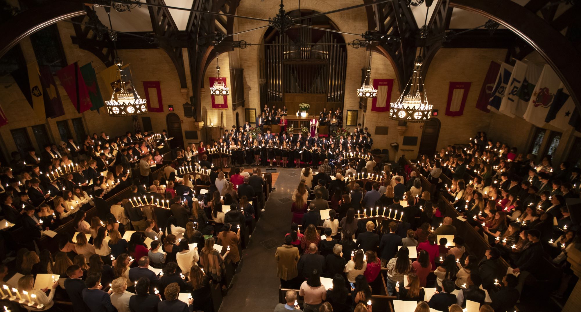 Students hold candles amid lit candelabras in an otherwise darkened Edith Memorial Chapel during the Lessons & Carols event.