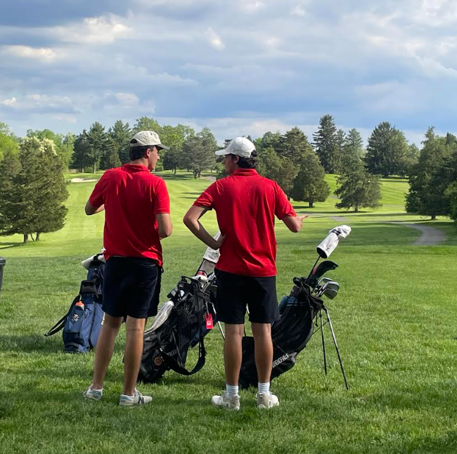 With the backs tot he camera, Harrison Emery ’25 and captain Quinn Mulhearn ’25 discuss strategy on the sixth tee during the Leibovit Cup final against Peddie.