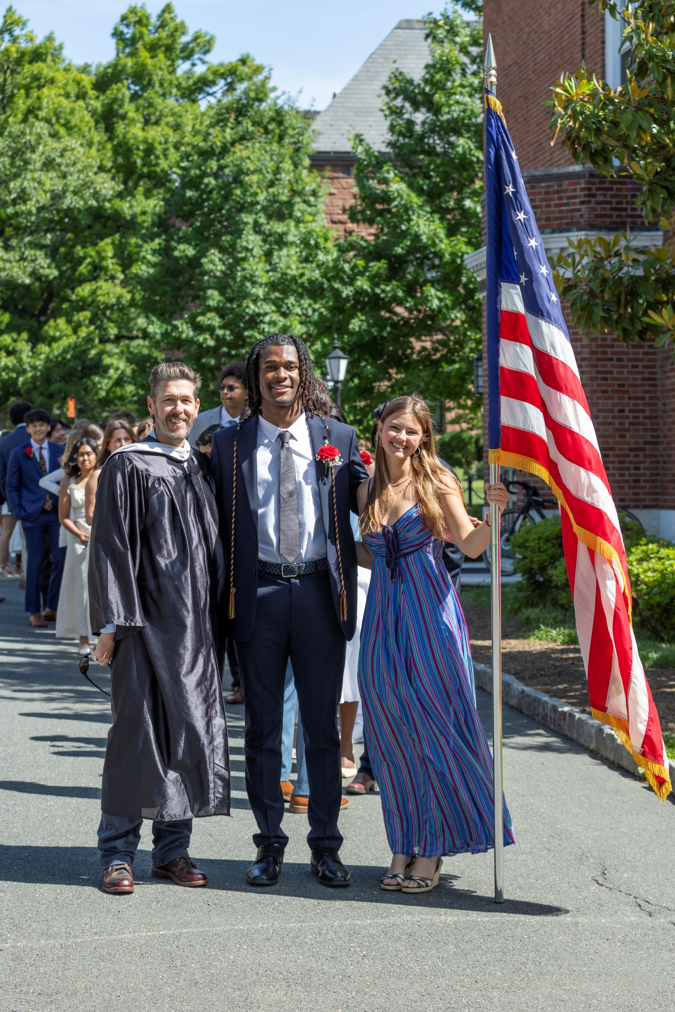 Dean of Students Blake Eldridge, graduating president Eli Lacey '25, and incoming president Sienna Kulynych ’26, who is holding the American flag.