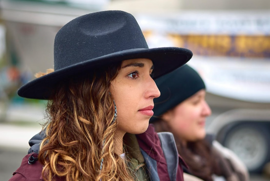 Hannah-Marie Garcia-Ladd '15 stares into the distance. She and others are wearing cold-weather boating gear, and Hannah-Marie is wearing a black brimmed hat.