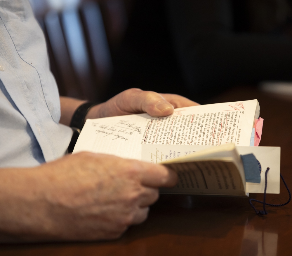 Closeup of the hands of Regan Kerney holding his Lincoln text showing his notes in the margins.