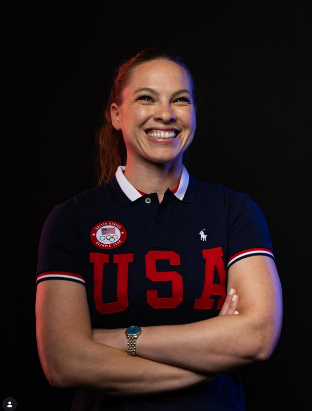 Olympic skeleton slider Kelly Curtis '08 is smiling with her arms crossed as she wears a navy-blue Team USA polo shirt.