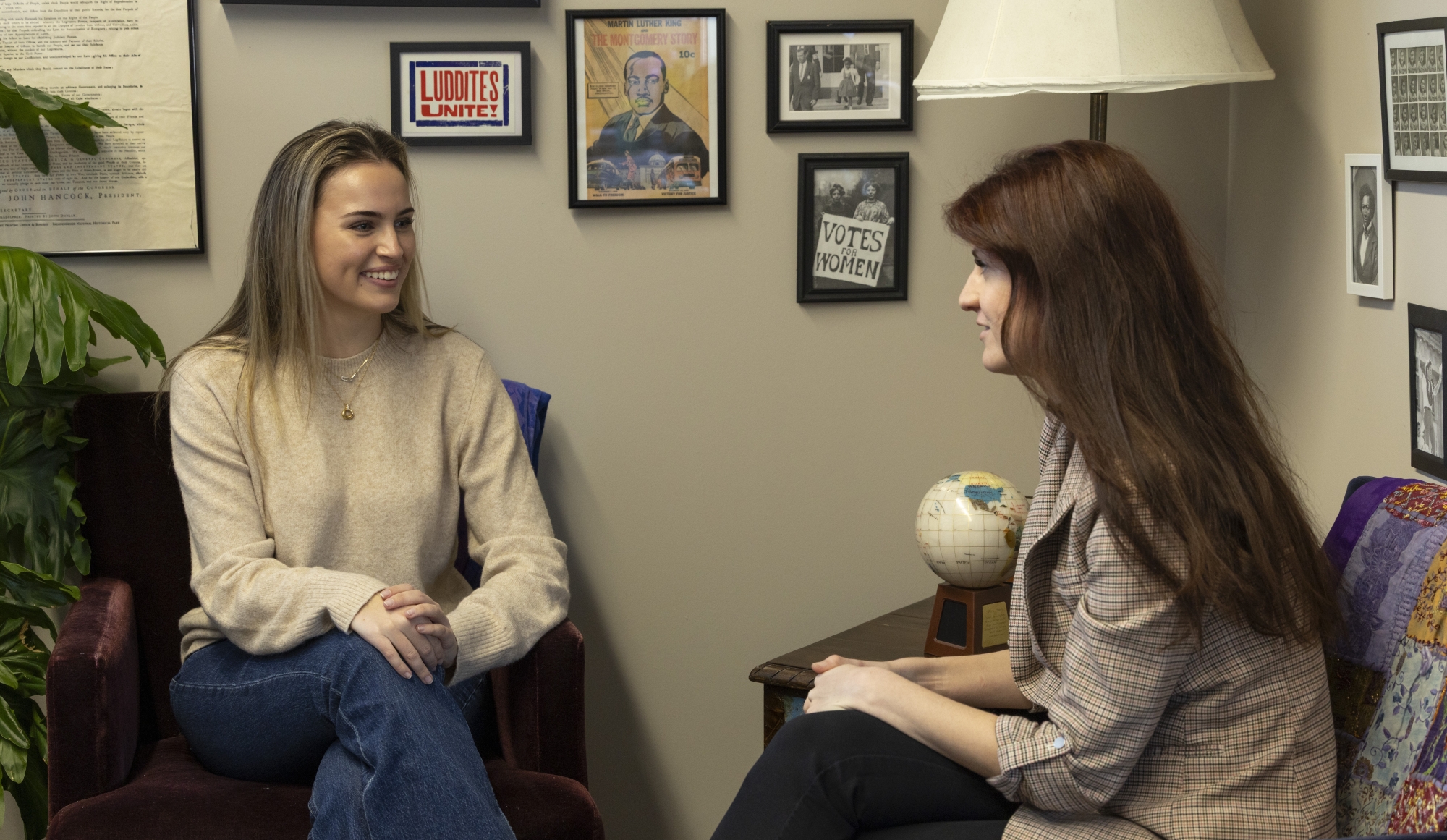 Leila Campbell '26, a student, is wearing a beige sweater and jeans and is smiling as she talks to history teacher Hazel Baldwin-Kress, who we see in profile as she looks at Leila.