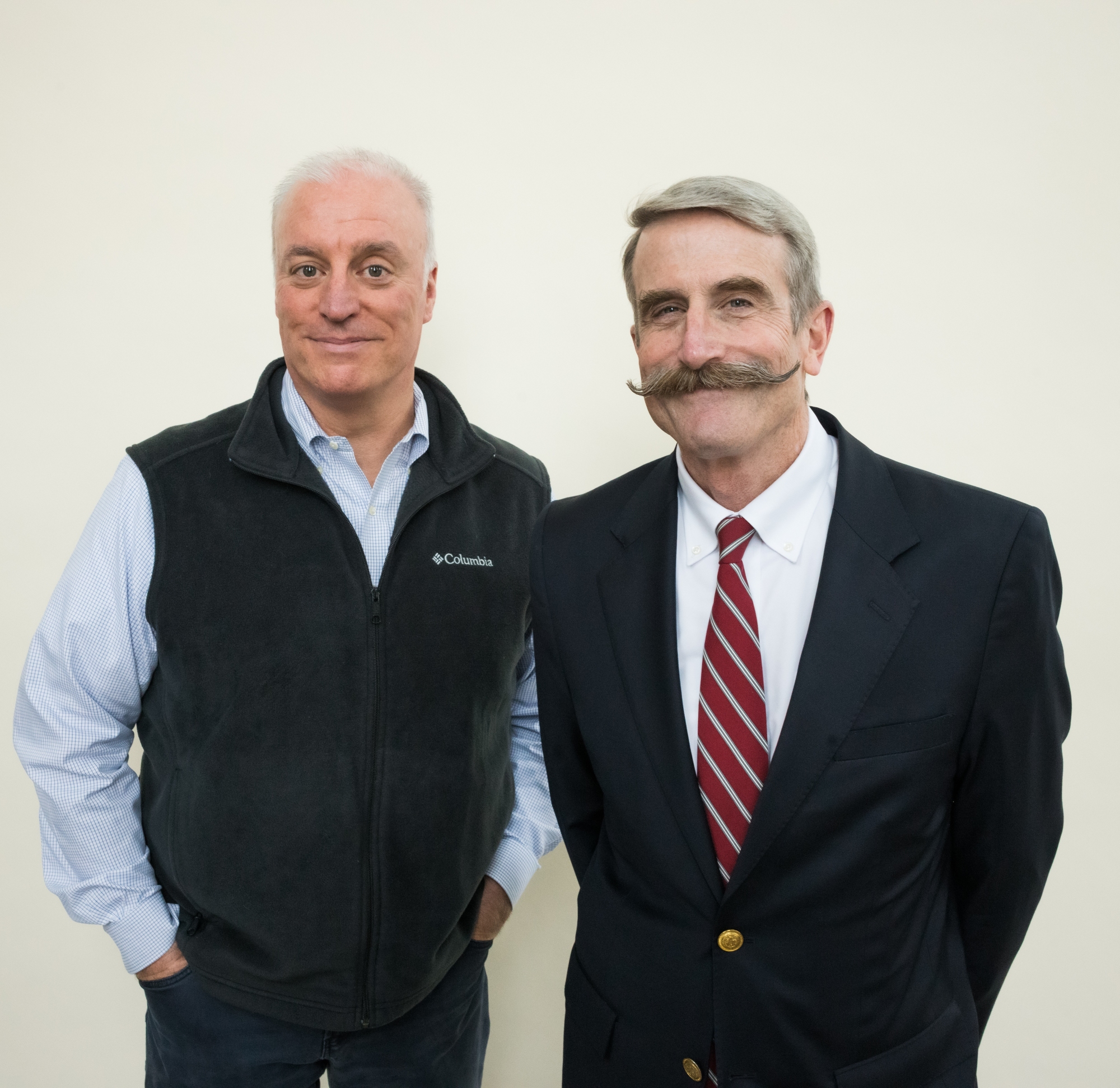 Lawrentian editor Sean Ramsden, wearing a dark gray fleece vest over a white and blue button-down shirt, with his hands in his pockets, stands beside a smiling Steve Murray, wearing a navy blazer, white shirt, and red and black tie, with his hands behind his back.
