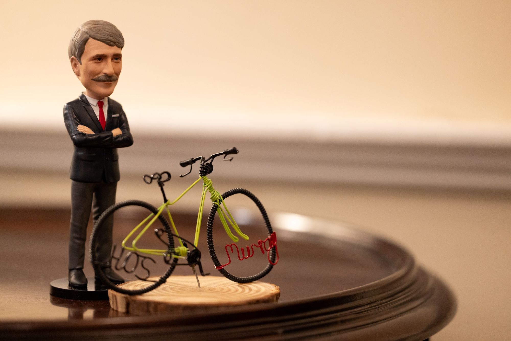 A figurine of Steve Murray standing beside a miniature replica of his yellow bicycle.